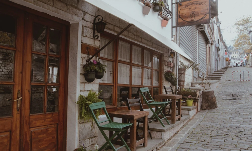 Calle empedrada del Bazar Viejo de Gjirokastër con mesas de café al aire libre