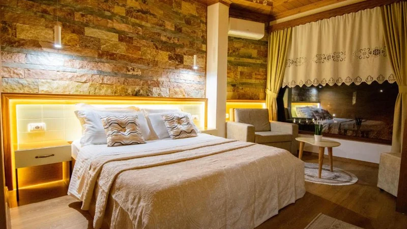 Pokój dwuosobowy Deluxe w Te Kalaja Rooms, z podwójnym łóżkiem i podświetloną kamienną ścianą